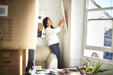 Woman taking a picture off the wall ready to pack while moving house