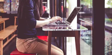 Beautiful young Asian girl working at a coffee shop with a laptop.female
