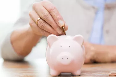 senior woman hand putting money to piggy bank