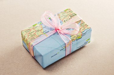 A bon voyage gift wrapped with map paper and pink bow