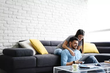 Girl Massaging Boyfriend On Sofa At Home