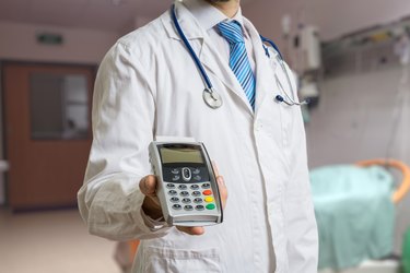 Doctor is holding payment terminal in hands