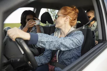 Young women friends in car with camera phone, enjoying road trip