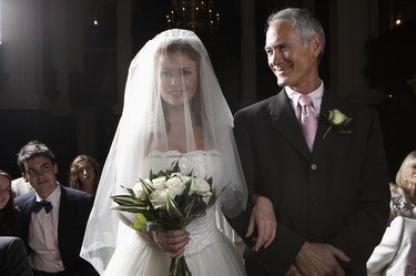Bride walking down aisle, arm linked with father's, smiling