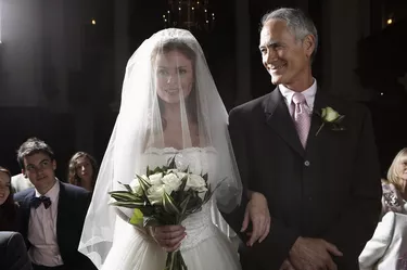 Bride walking down aisle, arm linked with father's, smiling