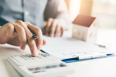 Home agents are using a calculator to calculate the loan period each month for the customer.