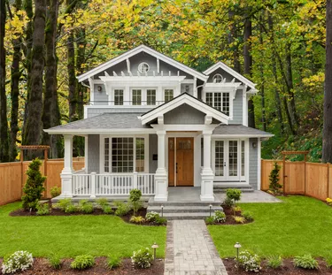 Beautiful Luxury Home Exterior with Green Grass and Landscaped yard. Colorful Forest forms Backdrop of Home.