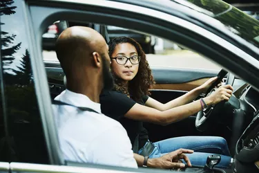 Daughter listening to fathers instructions while sitting in car before driving lesson