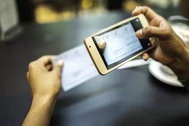 Young woman depositing check by phone in the cafe