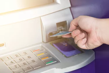 Hand inserting ATM credit card into bank machine