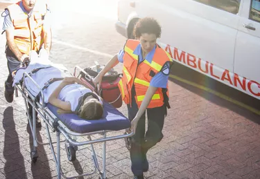 Paramedics wheeling patient in hospital parking lot