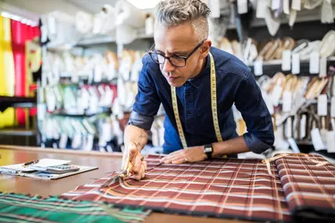 Male tailor cutting a textile at workbench