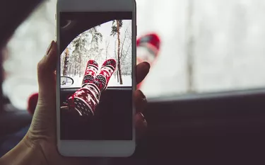 Girl makes a photo on her smartphone in the forest. The concept of the winter vacation relax.