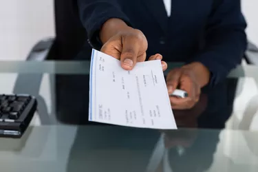 Person's Hand Giving Cheque