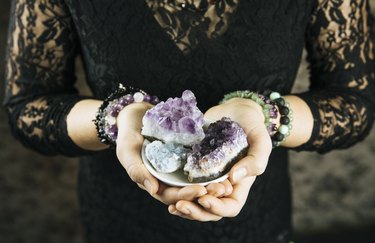 Healer woman holding different crystal clusters( amethyst, celestite) in palms hands. Close up view, using working with crystals concept.