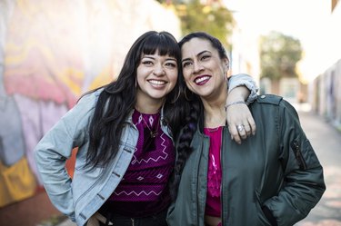 Two Young Latina Women Leaning Together, Smiling and Happy