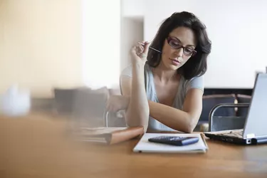 Woman sitting at desk looking at notebook