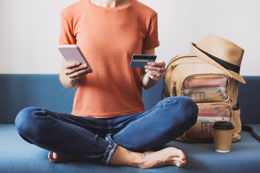 Young woman going on a travel and using smartphone and credit card.