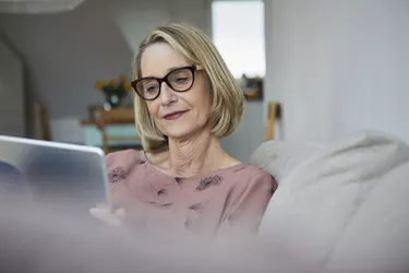 Mature woman at home using tablet on the sofa
