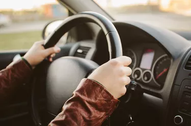 Close-up of hands on car steering wheel at 10 and 2