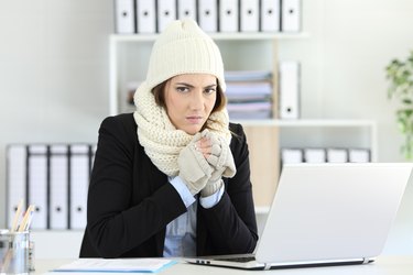 Angry businesswoman bundled up cold at office