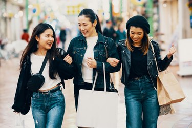 Three mid adult women with bags shopping in the city