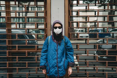 Portrait of a young woman with a protective mask in front of closed stores