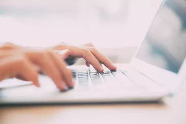 Close-up of male hands typing on laptop keyboard