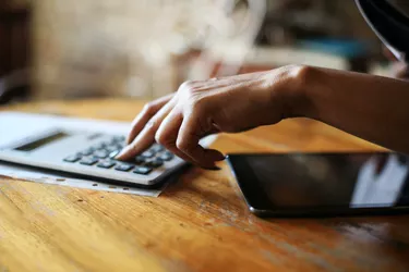 Close up of businesswoman hands using calculator.