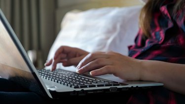freelancer hands type on black laptop keyboard closeup