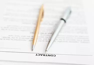 Can You Trade in a Vehicle Without a Signature From the Primary?sales contract and two pens close up