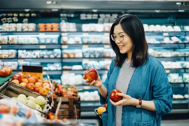 Young Asian woman shopping for fresh organic fruits in supermarket