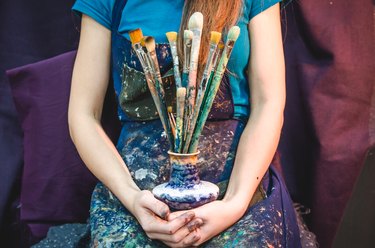 Closeup of female artist hands with paintbrushes