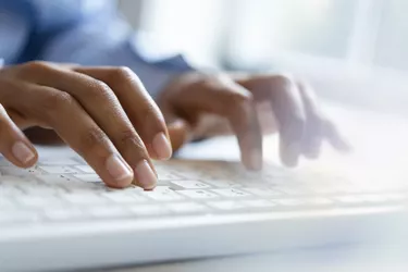 Hands of young woman typing on computer keyboard