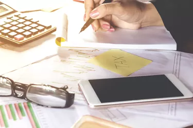 business woman hand calculating her monthly expenses during tax season with some bills