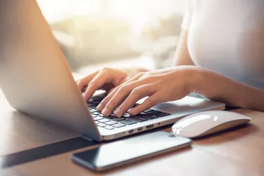 Closeup woman's hands typing on a laptop