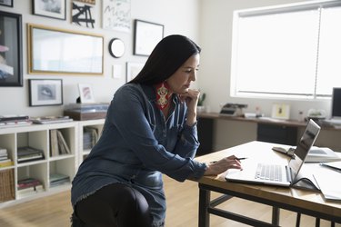 Focused creative businesswoman entrepreneur working at laptop in studio office