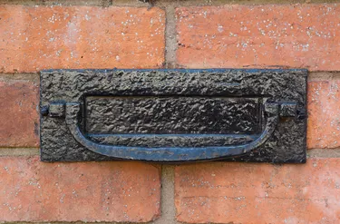 How Much Does a Brick Mailbox Cost? Black metal letter box on a red brick wall.