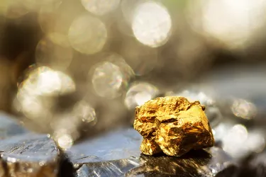 Golden bar on raw coal nuggets with soft focus and shiny background