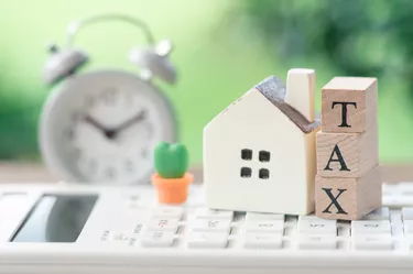 A model house model is placed on wood word TAX . as background property real estate concept with copy space for your text or design.