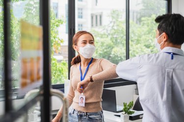 Asian businessman greeting with elbow bump or shaking elbow in working office to avoid touching due to infection of coronavirus covid-19, new normal life and social distancing concept