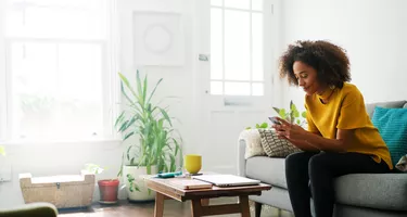 Woman sat on sofa using smart phone