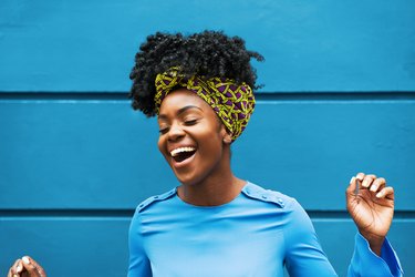 Joyous young Black woman in front of blue wall