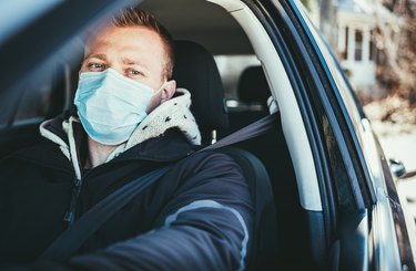 COVID-19, Young man wearing disposable face mask while driving