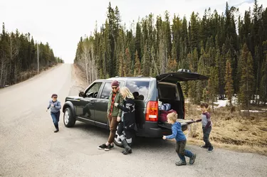 Family standing and playing outside SUV at remote roadside
