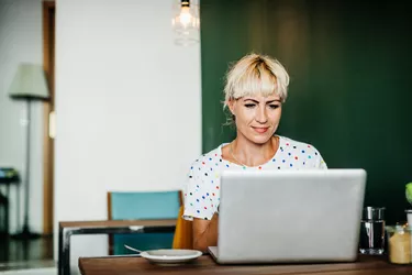 Woman Sitting Down In Cafe Using Lapotop