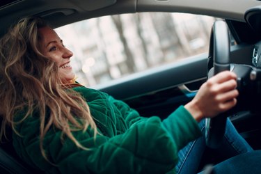 Young woman smiles and drives the car