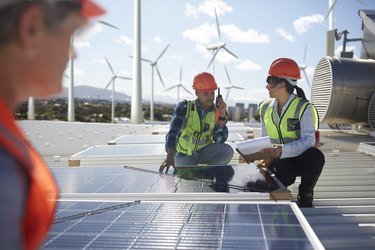 Engineers examining solar panels at alternative energy power plant