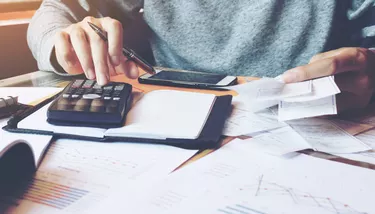 Man using calculator and calculate bills in home office.