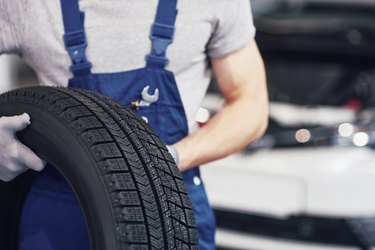 Mechanic holding a tire tire at the repair garage. replacement of winter and summer tires
